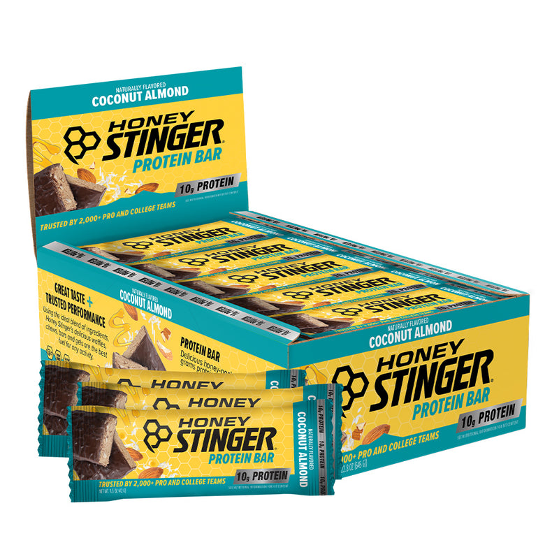 A display box of Honey Stinger Protein Bar in Coconut Almond flavor, with several individual bars pulled from the front, shown on a plain white background.