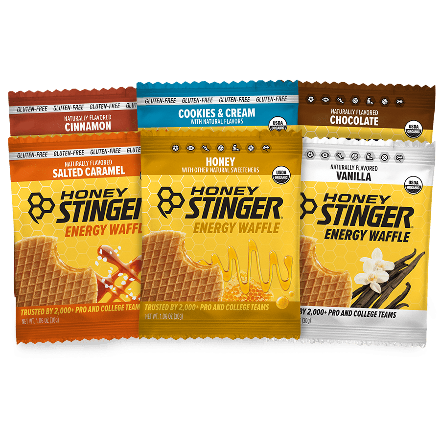 Six packages of Honey Stinger energy waffles in different flavors on a white background