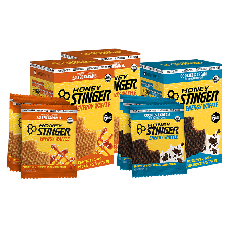 Honey Stinger energy waffle packages in salted caramel and cookies & cream flavors on a white background.