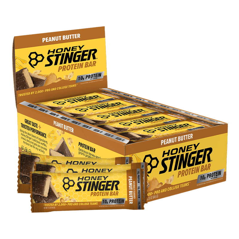 A Honey Stinger Protein Bar box in Peanut Butter flavor, shown with several individual protein bars in front on a clean white background.